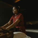 Professional masseuse performing relaxing spa massage in dimly lit room.