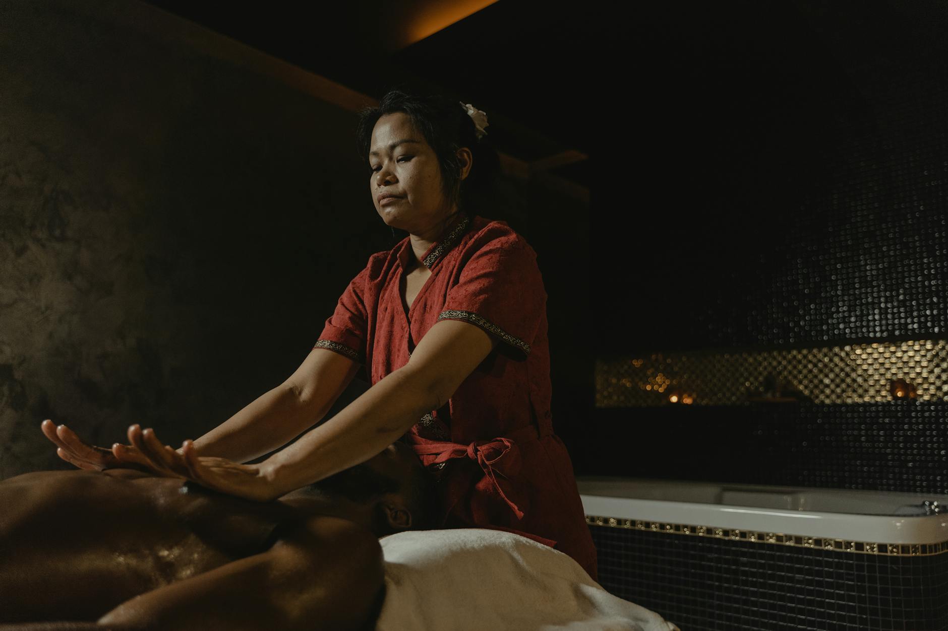 Professional masseuse performing relaxing spa massage in dimly lit room.