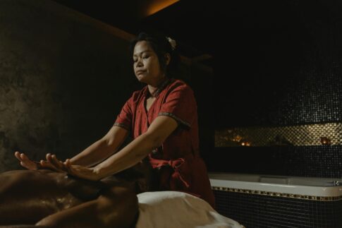 Professional masseuse performing relaxing spa massage in dimly lit room.