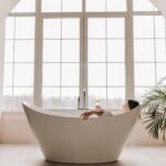 A serene scene of a woman enjoying a glass of wine while relaxing in a modern bathtub indoors.