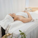 Woman enjoying a calming spa treatment indoors, wrapped in towels for ultimate relaxation.