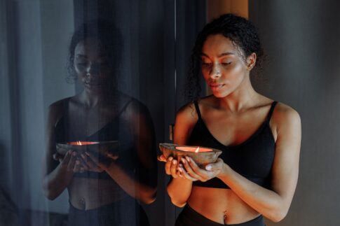 Peaceful woman holding a lit candle, reflecting calm and tranquility indoors.