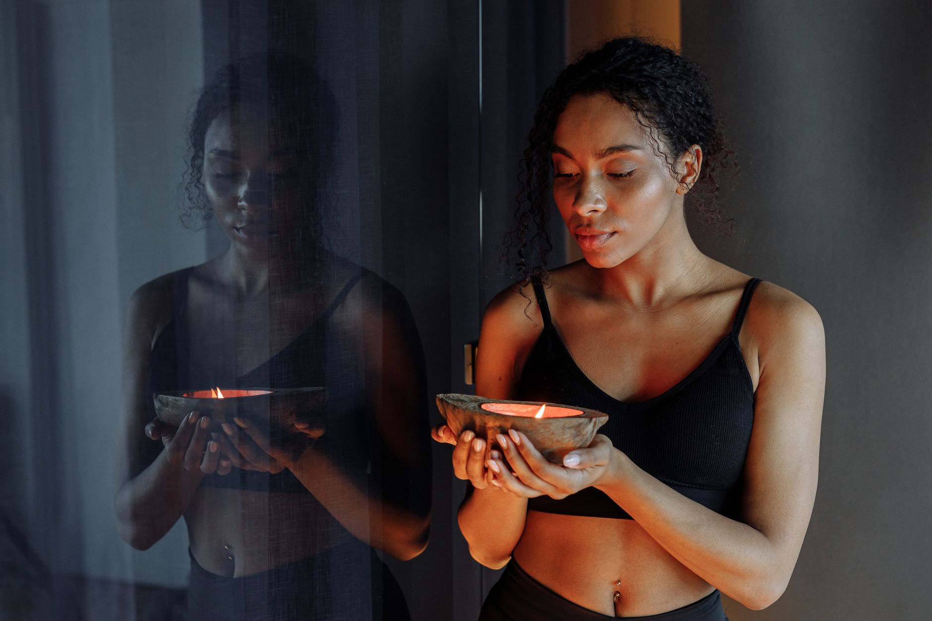 Peaceful woman holding a lit candle, reflecting calm and tranquility indoors.