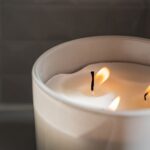 A close-up of a lit candle in a ceramic jar, creating a cozy atmosphere.