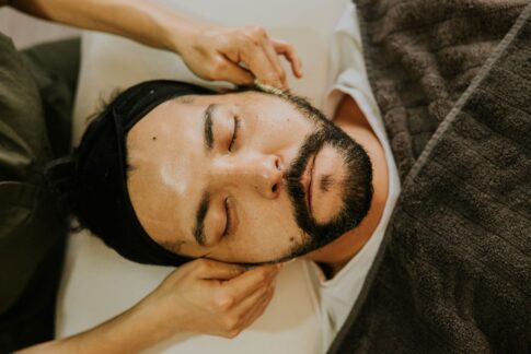 Close-up of a man receiving a facial massage with eyes closed, promoting relaxation and skincare.